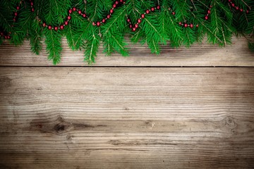 Fototapeta na wymiar Pine tree border with red garland on old wooden background