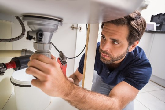 Plumber fixing under the sink