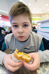 Teen boy eats  hamburger n Cafe