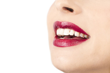 Obraz premium Rostro de mujer con labios pintados sonrisa en un fondo blanco aislado. Vista de frente y de cerca. Copy space