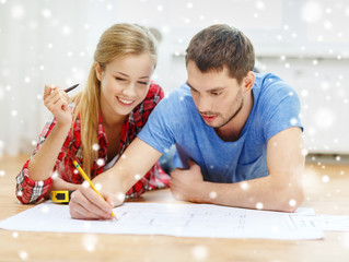 smiling couple with  blueprint at home