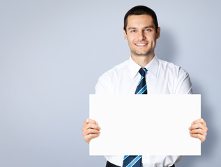 Businessman showing blank signboard, over grey