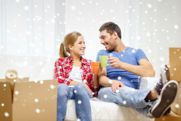 smiling couple drinking tea or coffee at new home