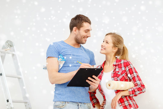 smiling couple with clipboard and wallpaper roll