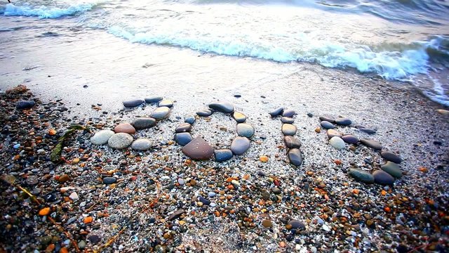 Christmas 2015 made of small stones on the sandy beach. HD.