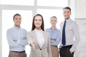 smiling businesswoman in office with team on back