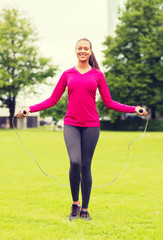 smiling woman exercising with jump-rope outdoors