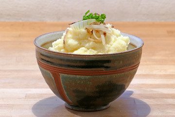 rustic ceramic bowl with mashed potatoes, fried onion and fresh