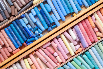 Multicolored pastel crayons in wooden artist box closeup, top vi