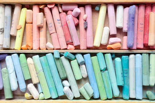 Pastel crayons in wooden artist box closeup, top view.
