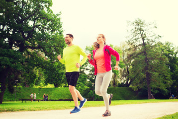 Obraz premium smiling couple with earphones running outdoors