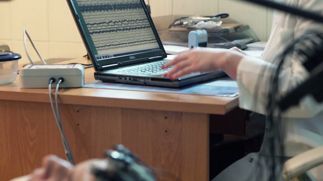 Woman having brain scan and doctor using laptop in hospital
