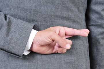 man in suit crossing his fingers in his back