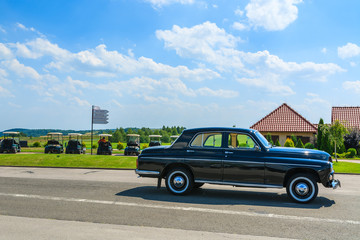 Old classic black car parks on street in rural area of Poland
