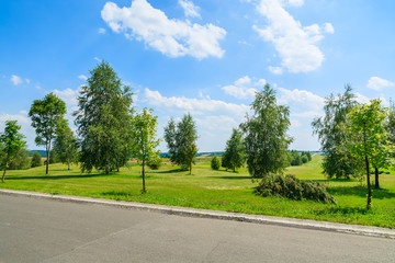 Fototapeta na wymiar Countryside road along green fields in summer landscape, Poland