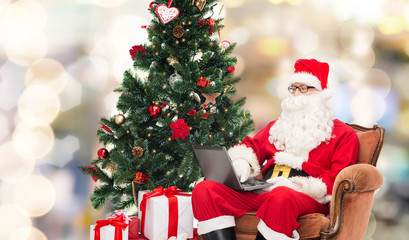 man in costume of santa claus with laptop