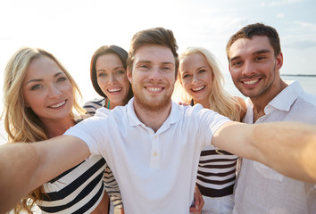 happy friends on beach and taking selfie