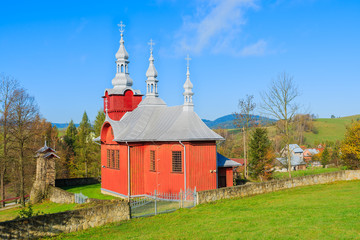 Red wooden church on green meadow in Czyrna village, Poland