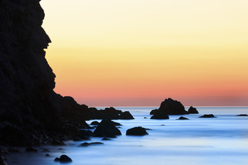 Sunrise on beach with rocks and sea