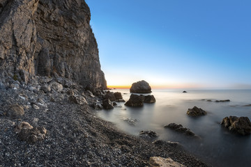 Sunrise on beach with rocks and sea