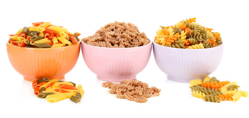 Assortment of colorful pasta in color bowls isolated on white