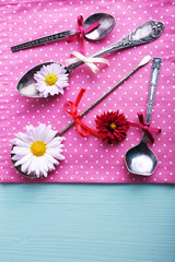 Metal spoons on pink polka dot napkin on wooden background