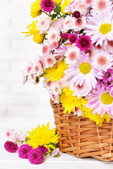 Obraz na płótnie Canvas Beautiful flowers in wicker basket on table on light background