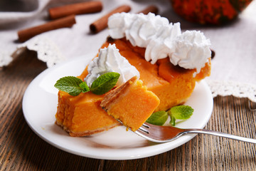 Piece of homemade pumpkin pie on plate on wooden background
