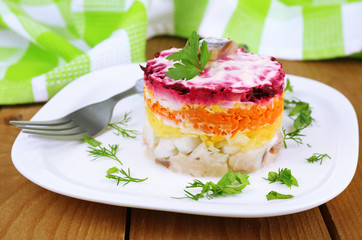 Russian herring salad on plate on wooden table background
