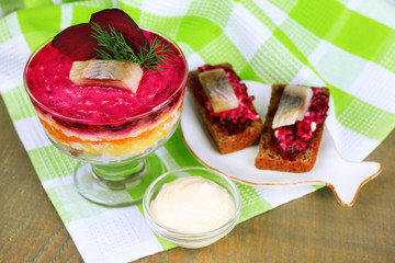 Russian herring salad in glass bowl and sandwiches with salted