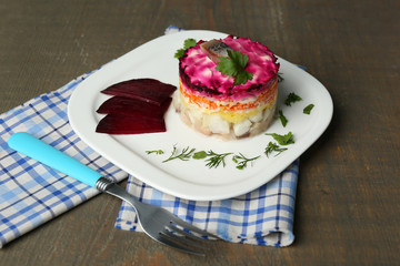 Russian herring salad on plate on wooden table background