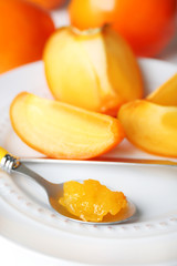 Ripe persimmons on plate, on wooden background