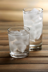 Glasses with ice cubes on wooden table