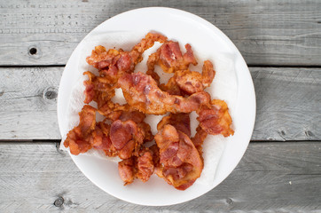Fried bacon on a ceramic plate against wooden background