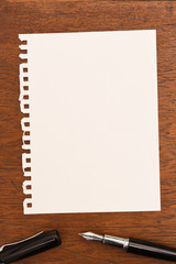 Pen and notebook on wooden background.