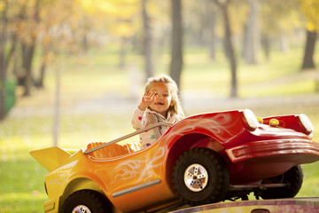 Little Girl Riding a Car In Amusement Park Outdoor