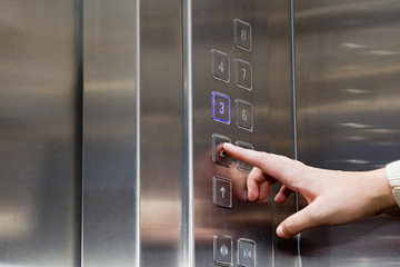 Female finger presses the button for the elevator