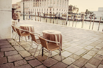 Cafe tables near river in Venice, Italy