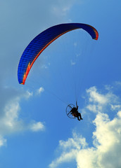 Paragliding man against blue sky