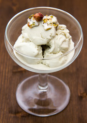 Cup with pistachio ice cream on wooden table close up view