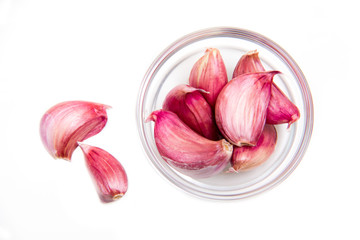 Garlic in glass bowl on a white background seen from above
