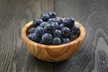 ripe isabella grapes in wood bowl on table
