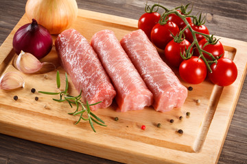 Raw pork chops on cutting board and vegetables