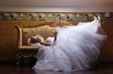 Extravagant bride on sofa, holding a glass of wine