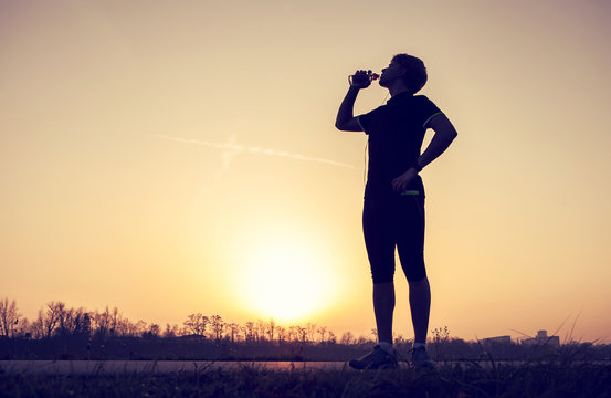 Runner drinks water after training