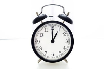 Oldfashioned black glossy alarm clock showing 1 o'clock