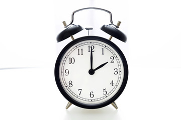 Oldfashioned black glossy alarm clock showing 2 o'clock