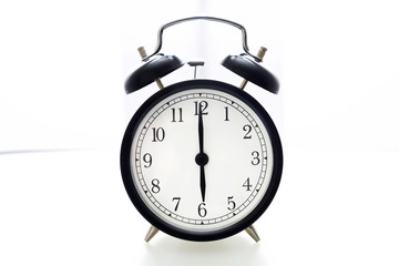 Oldfashioned black glossy alarm clock showing 6 o'clock