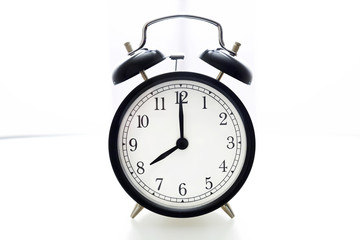 Oldfashioned black glossy alarm clock showing 8 o'clock