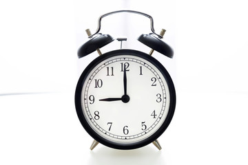 Oldfashioned black glossy alarm clock showing 8 o'clock